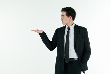 Portrait of self-confidence young and handsome Asian businessman in black suit standing and use hand present and advertising something, copy space studio shot isolated on white background