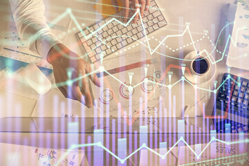 Multi exposure of man's hands typing over computer keyboard and forex graph hologram drawing. Top view. Financial markets concept.