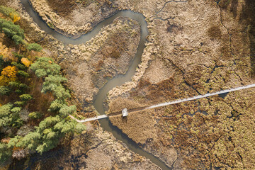 Obraz na płótnie Canvas River, wooden footbridge and forest in Kazdanga, Latvia. Captured from above.