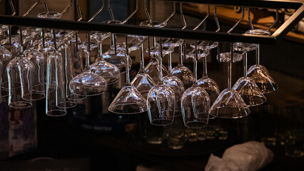 A set of glass clear glasses hangs above the bar on a metal mount. Taken in a low key