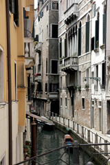 
A canal street in Venice. A narrow water alley with high old houses around. 