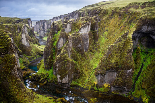 Majestic Fjaðrárgljúfur, Canyon Fardrargljufur Island Iceland during a rainy and wet days. Canyon with green flora and blue water in tranquility.