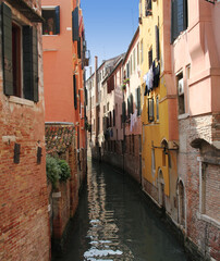 Fototapeta na wymiar A canal street in Venice. A narrow water alley with high old houses around. 