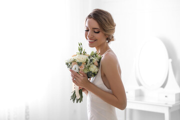 Young bride with beautiful wedding bouquet in room