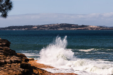 big waves crashing against rocky shoreline in Tasmania, Australia