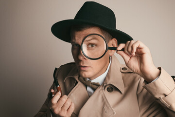 Male detective with smoking pipe looking through magnifying glass on beige background - obrazy, fototapety, plakaty
