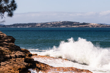 big waves crashing against rocky shoreline in Tasmania, Australia