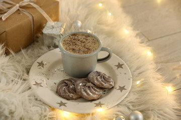 Tasty hot drink, cookies, gift and Christmas lights on fur