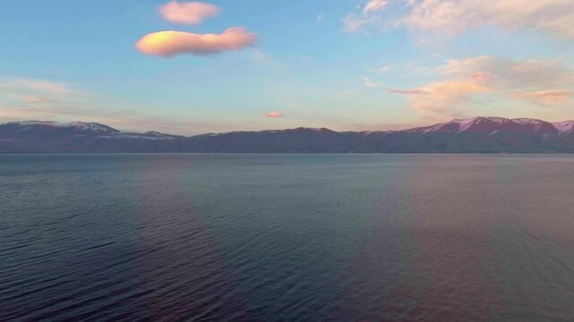 Freshwater mountains lake Sevan and beautiful sky heaven during sunset aerial drone fly over footage.
