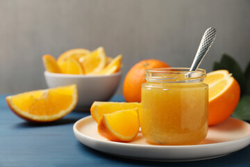 Delicious orange marmalade and fruit slices on blue wooden table