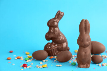 Chocolate Easter bunnies, eggs and candies on light blue background. Space for text