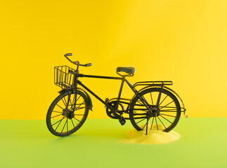 black old retro vintage bike and yellow sand on sunny yellow and light green background. Minimal creative abstract concept.