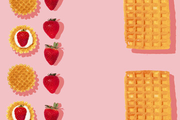 Creative pattern or frame made with strawberries and waffles on pastel pink background. Happy and fun breakfast or brunch idea with fruits. Flat lay. Strawberry fruit concept.