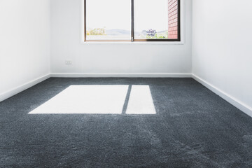 empty room with brand new grey blue carpet laid on the floor and freshly painted white walls, home...