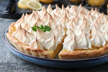 Obraz na płótnie Canvas Cut delicious lemon meringue pie on grey table, closeup