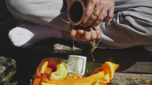 Close up of male hindu offering water money and food to Gods from a copper vase in hindu puya.