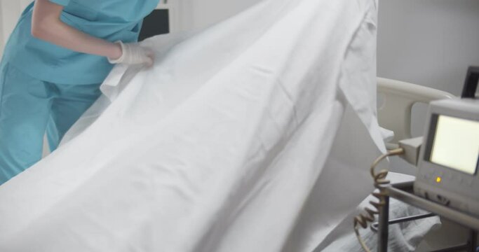 Nurse covering dead patient with sheet in emergency room