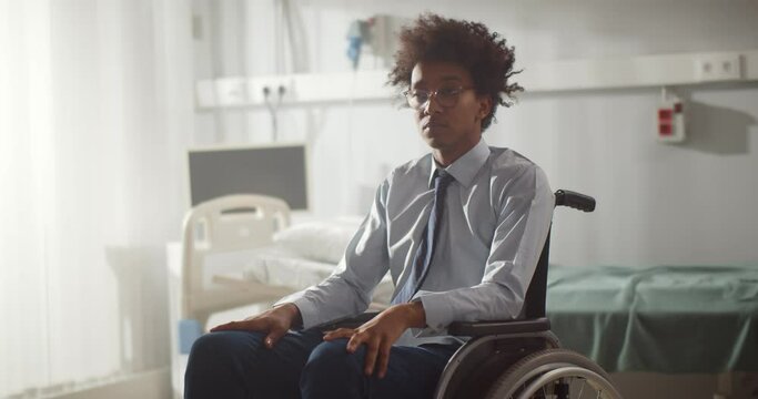 Portrait of young paralyzed afro man sitting in wheelchair at hospital