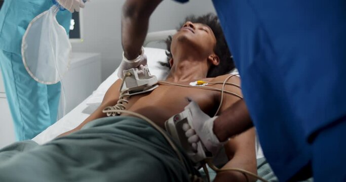 Doctors give resuscitation to afro male patient in emergency room.