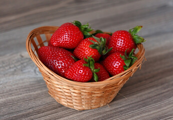 A basket of ripe strawberries on a wooden table. Image with selective focus.