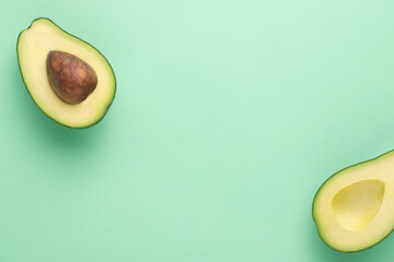 Halved avocado on a green background with copy space.