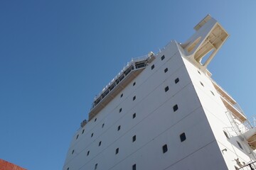 View on the white superstructure with navigational bridge of the merchant container vessel from main deck during sunny day with blue, azure sky and a lot of copy space. © Lucia