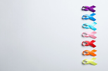 Different colorful ribbons on white background, flat lay with space for text. World Cancer Day