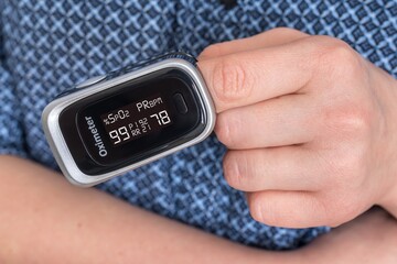 Woman with oximeter is measuring oxygen saturation and pulse
