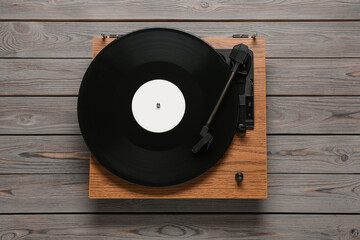 Turntable with vinyl record on wooden background, top view