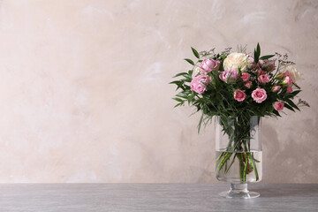 Beautiful bouquet with roses on table against grey background, space for text