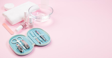Spa set equipment for manicure or pedicure with nail coat or polish, towel and water, on pink background, horizontal, copy space