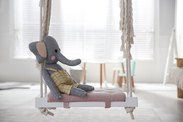 Beautiful swing with toy elephant in room. Stylish interior design