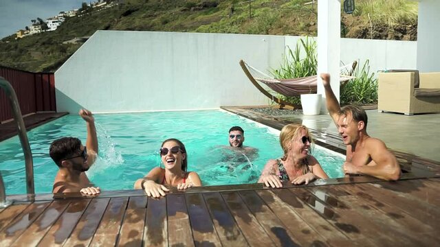 Happy friends enjoying summer day in swimming pool - Young people having fun in exclusive private villa - Youth vacation lifestyle concept