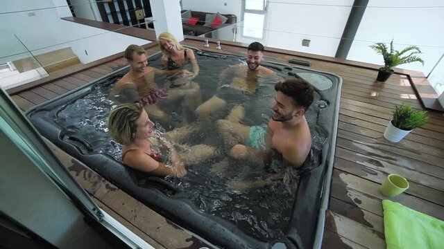 Happy friends enjoying vacations in jacuzzi luxury house - Young people having fun together in hot tub - Youth millennial generation and wellness lifestyle holidays