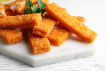 Tasty fresh fish fingers served on white wooden table, closeup