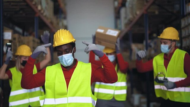 Multiracial team having fun dancing inside warehouse while wearing face mask during corona virus outbreak - Logistic and industrial concept	