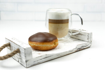 A glazed donut lieы on a wooden tray for early breakfast