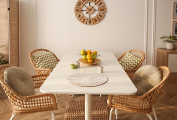 Stylish white dining table and wicker chairs in room. Interior design