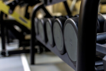 Fototapeta na wymiar Gym background Fitness equipment dumbbells weight for a workout. Background image of dumbbells in row on equipment stand in modern gym. Dumbbells on the racks at the gym,exercise and relaxing concept.