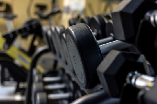 Gym background Fitness equipment dumbbells weight for a workout. Background image of dumbbells in row on equipment stand in modern gym. Dumbbells on the racks at the gym,exercise and relaxing concept.