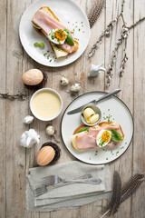 Easter breakfast with golden toasted Easter bread with butter and cheese and chives and basil with Easter decoration on light wooden background and delicious yellow sauce