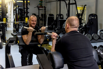 Caucasian young male weight training person doing a biceps curl in fitness center. Young handsome...