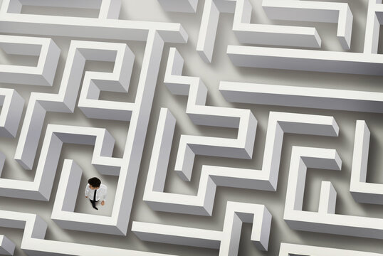 Thoughtful businessman trying to find way out of maze, above view