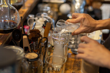 The bartender is pouring the coconut water mixed with the coconut pulp into a clear glass. To mix drinks for customers in coffee shops