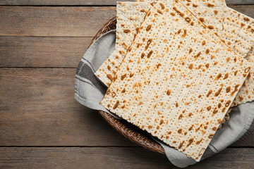 Traditional matzos in basket on wooden table, top view