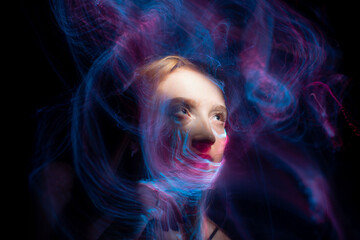beautiful girl model with cosmic make-up on face, blue and purple color on dark background , lightpaintinf foto
