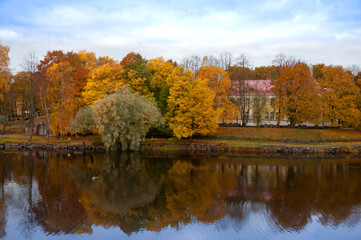 Fototapeta na wymiar Yellow, orange, red autumn trees near pond with amazing water reflection in beautiful park on the warm day with clear blue sky, Karelia, Russia