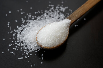 sugar crystals on a wooden tea spoon isolated on black