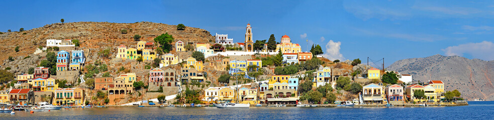 Fototapeta na wymiar Symi – die schönste griechischen Insel mit unzählige Minivillen in Pastellfarben an einen Hügel geklatscht 