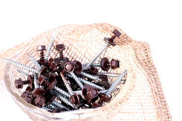Roofing screws and burlap in a glass container on a white background.